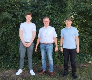 3 Personen vor einer grünen Hecke