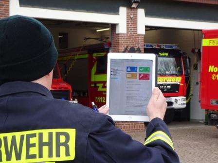 Feuerwehrangehöriger mit Tablet bei der Gefährdungsbeurteilung
