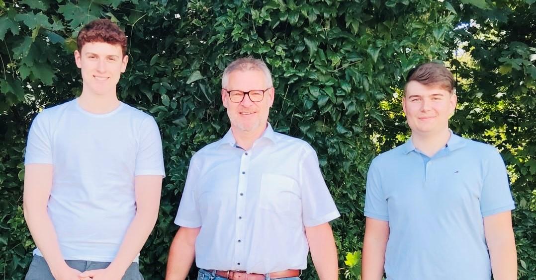 3 Personen vor einer grünen Hecke